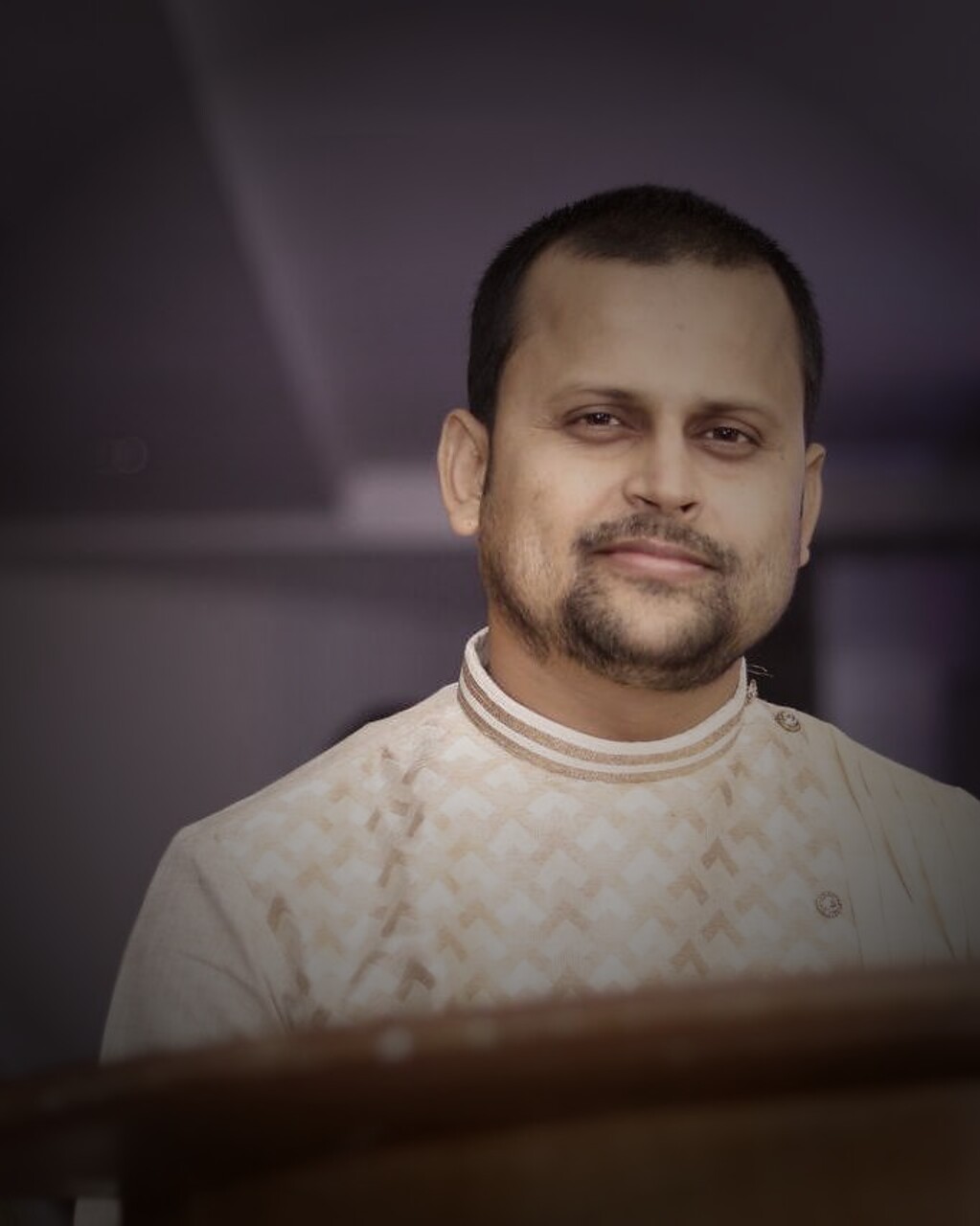 Deepak Jha at the lectern in an ivory kurta, mid-event